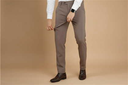Person wearing brown dress pants on a beige background