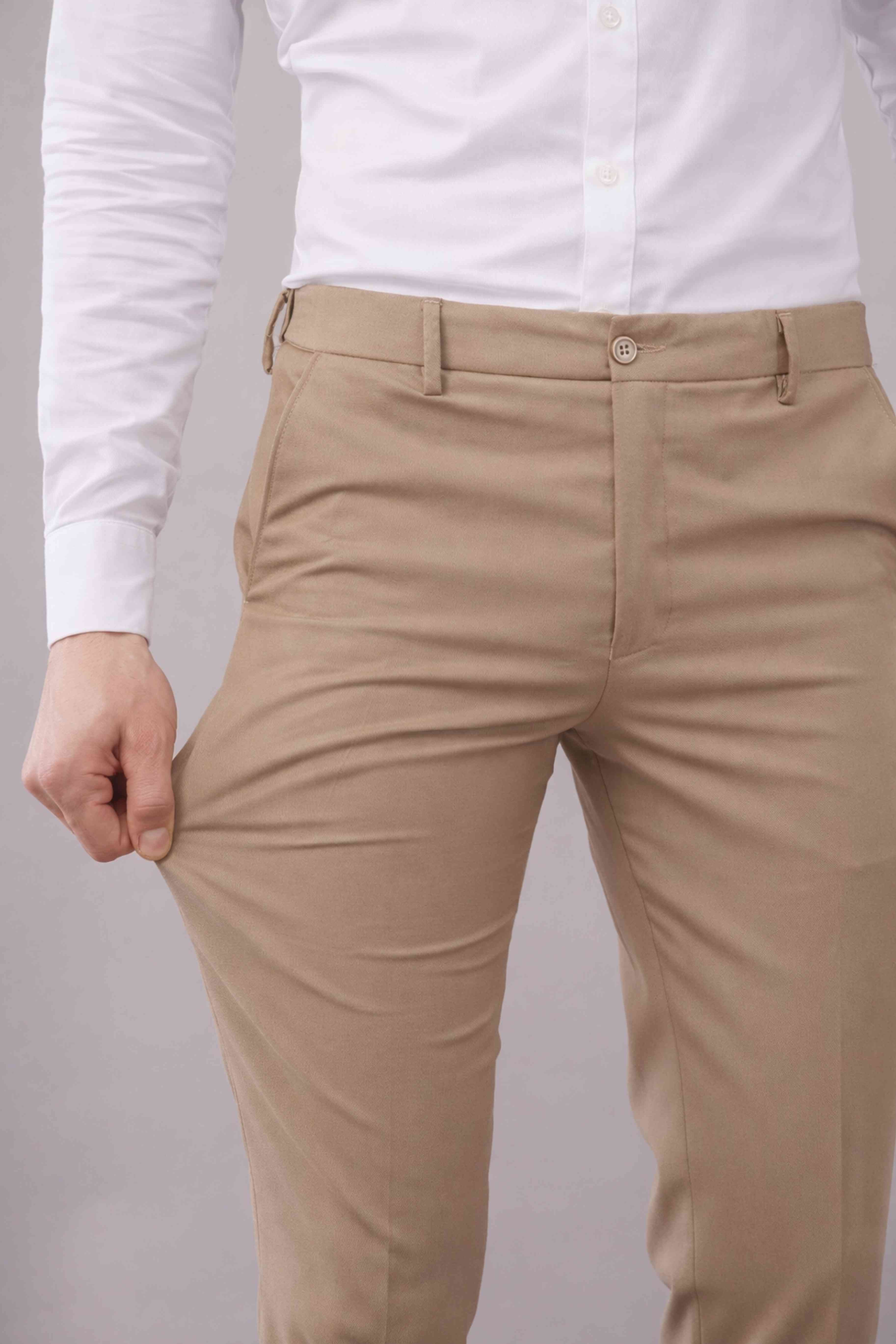 Beige pants worn with a white shirt on a plain background