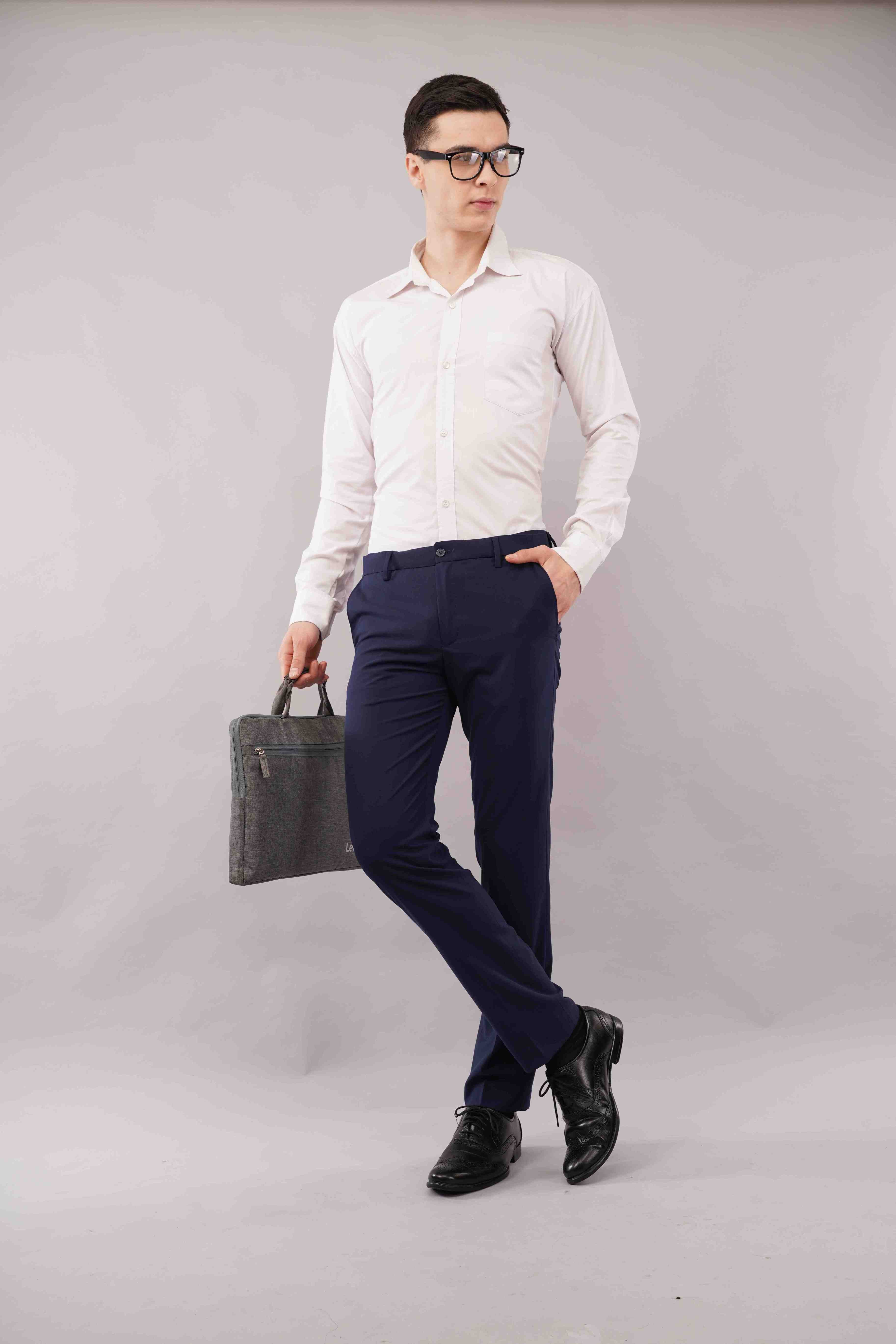 Man wearing a white shirt, blue flexiwaist pants and black shoes holding a black briefcase