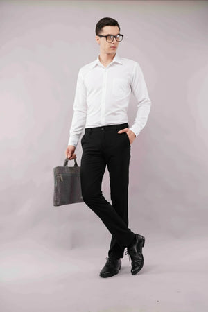 Man wearing a white shirt, 2 way flexiwaist black pants, and holding a black bag