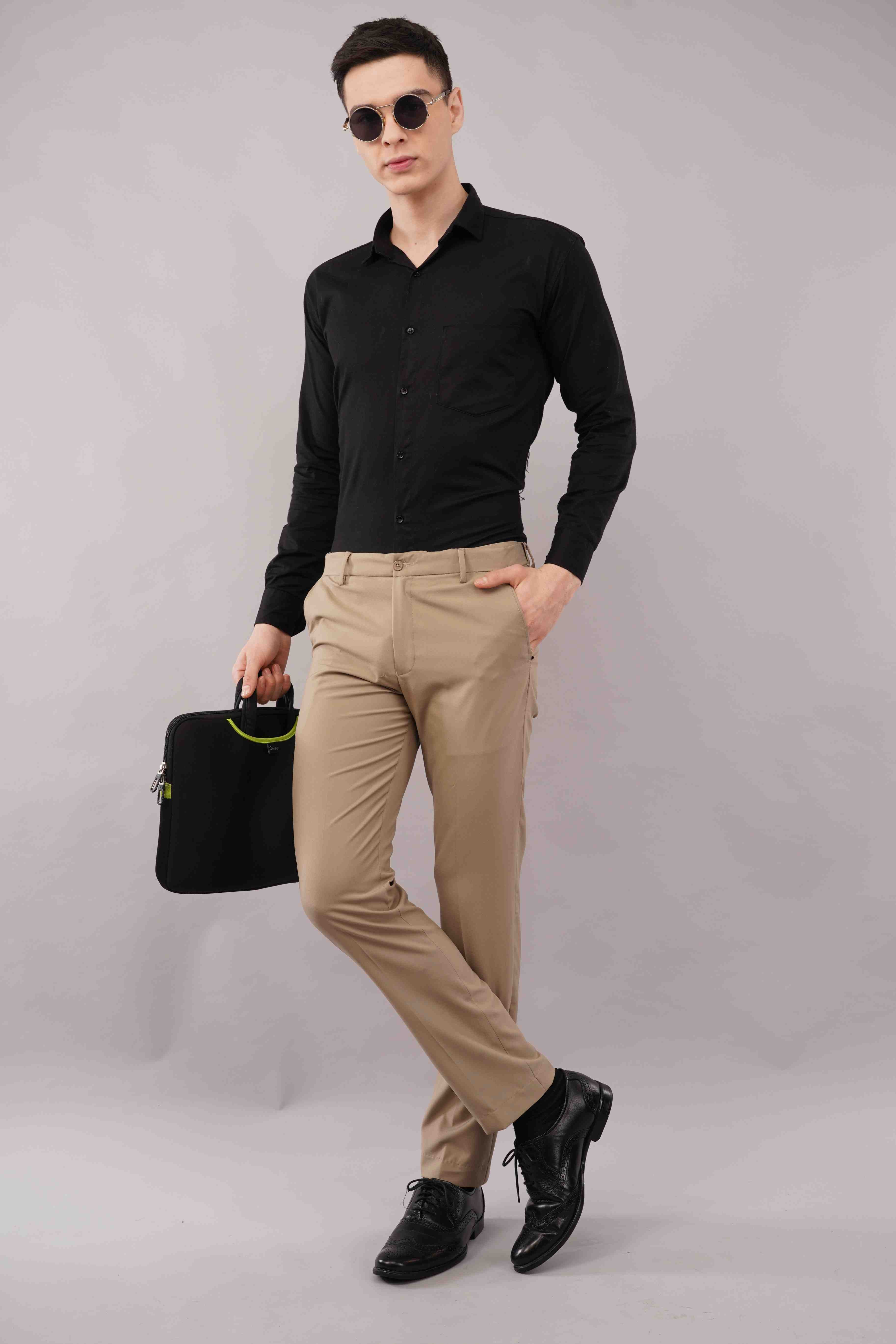 Man wearing a black shirt, beige pants, and sunglasses holding a black briefcase on a gray background
