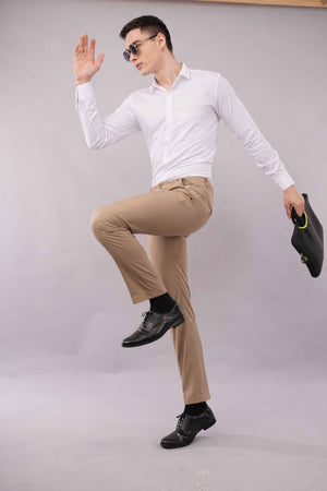 Man in white shirt and 2 way beige pants posing with a shoe