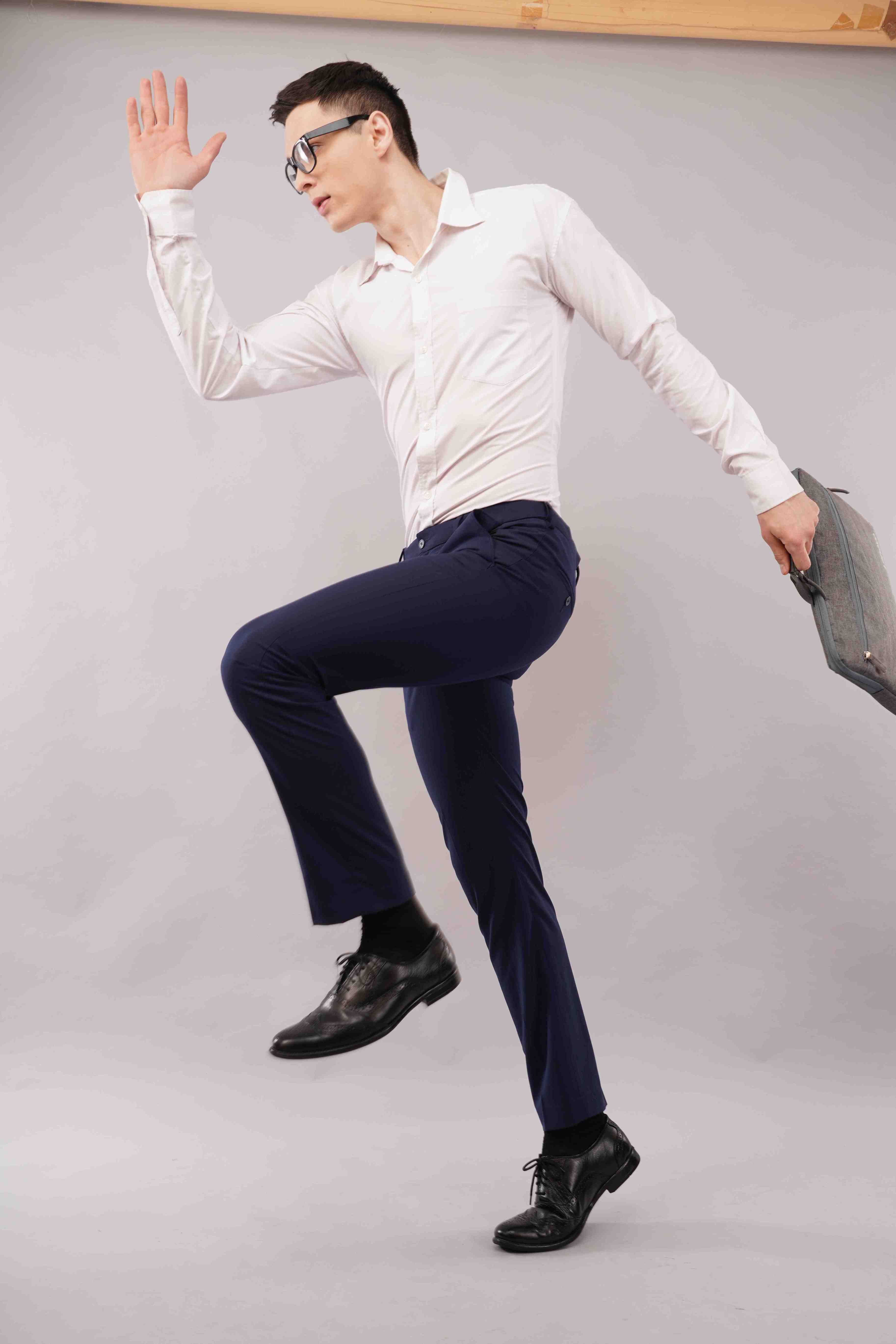 Man in formal attire posing against a plain background